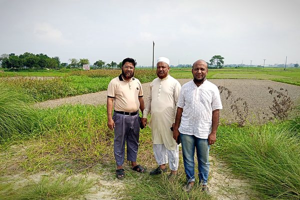 Team at the field edge beside a prepared approach road and paddy plots